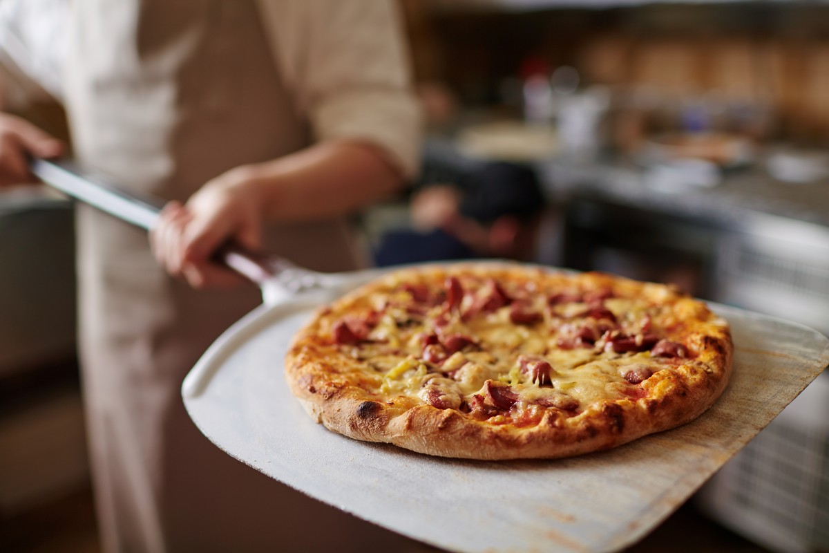 close-up-of-cook-holding-pizza-on-peel